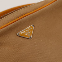 Détail plaque logo Prada Milano sur toile beige — AMANA Vintage
